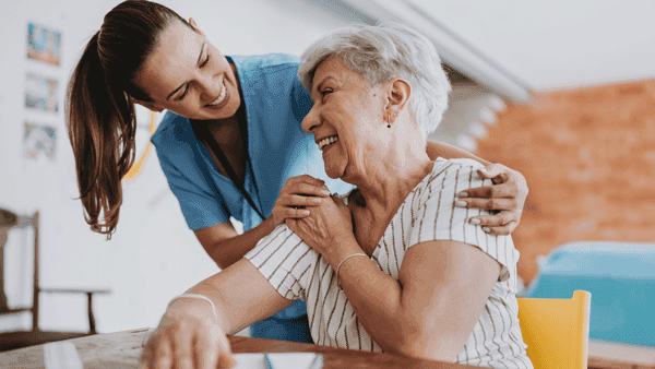 A carer sharing a warm, happy moment with an older woman
